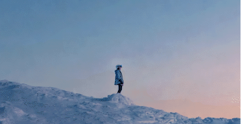 Eine Person steht in einer Schneelandschaft. Es fallen Meteoriten vom Himmel. Es ist eine Abendstimmung.